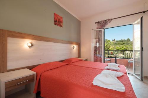 a bedroom with a red bed and a large window at Rainbow in Arillas