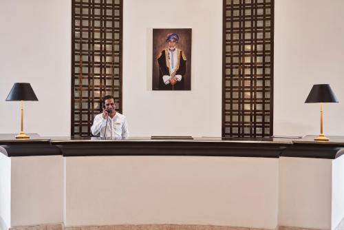 a man taking a picture behind a reception desk at Juweira Boutique Hotel Adult only in Salalah