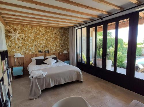 - une chambre avec un lit et un mur de fenêtres dans l'établissement Calme et piscine au cœur du Luberon, à Cabrières-dʼAigues