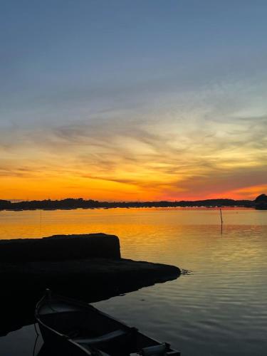 un bateau assis sur la rive d'un lac au coucher du soleil dans l'établissement Location logement entier Maison bourg, proche plages, Arradon - Morbihan, à Arradon