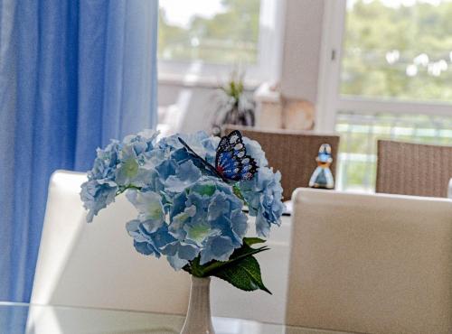 a vase with blue flowers and a butterfly on a table at Stone House Blaca in Blato