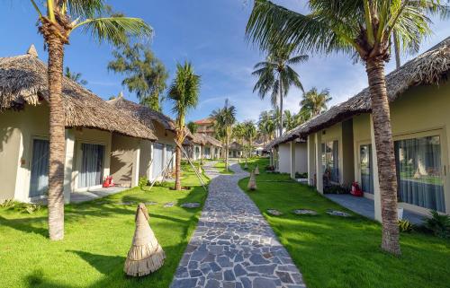 a path through a resort yard with palm trees at Coco Cottage Beachfront Resort in Mui Ne