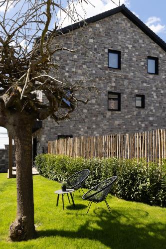 two chairs sitting next to a tree in a yard at Suite Cocoon By M in Francorchamps