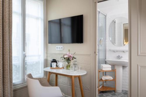 a bathroom with a table and a sink and a television at Hôtel Madeleine Haussmann in Paris