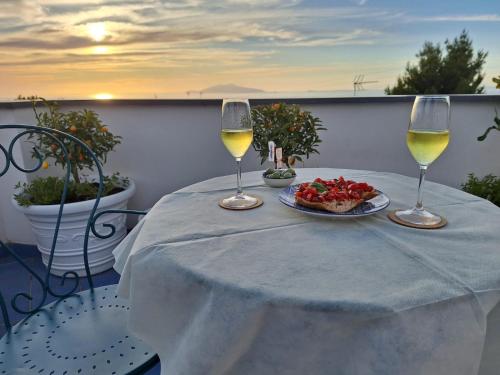 a table with a plate of food and two glasses of wine at B&B Casa Angelina in Anacapri