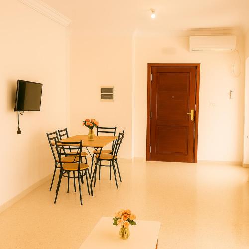 a dining room with a table and chairs and a door at Cosy Residence Amira in Monastir