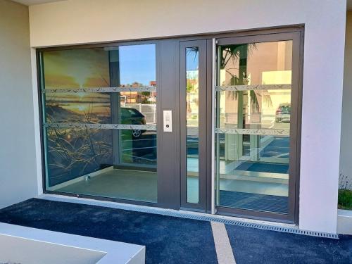 un accès à un bâtiment avec des portes coulissantes en verre dans l'établissement AYAPI - Appartement neuf 3 étoiles avec terrasse et jardin - bord de plage, à Marseillan