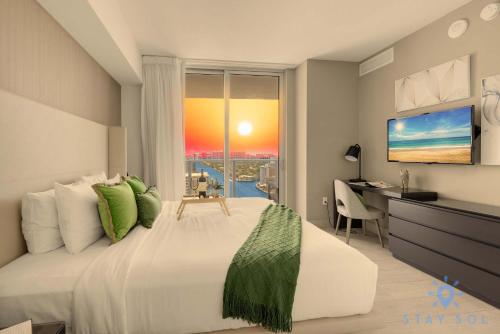 ein Schlafzimmer mit einem Bett mit Schreibtisch und einem Fenster in der Unterkunft Luxury 3 Br - Corner Balcony - Panoramic View - Pools in Hollywood