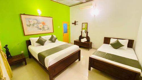 two beds in a room with green walls at AYUBO Villa in Negombo