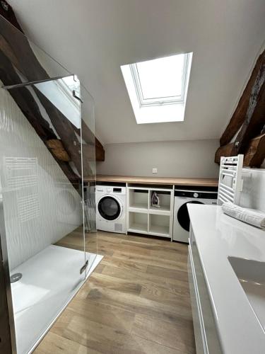 une salle de bain avec un puits de lumière et une machine à laver dans l'établissement Les Ecuries, sur un domaine châtelain, à Isle