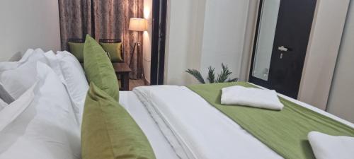 a bed with white sheets and green pillows at Around Stays-House Of Tourists in Rishīkesh