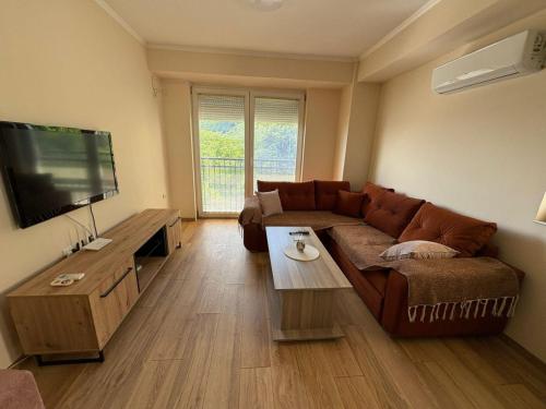 a living room with a brown couch and a flat screen tv at Family Apartment in Skopje
