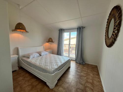 une chambre avec un lit blanc et une fenêtre dans l'établissement Domaine de vacances à 600m de la plage villa climatisée 3 chambres 7 couchages terrasse WIFI animations et piscines en supplément LRPDSD7, à Portiragnes