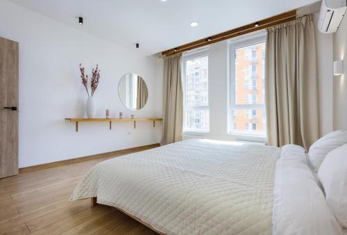 a white bedroom with a bed and a large window at 45 Kyiv Lovely Apartment in Nyvky Park in Kyiv
