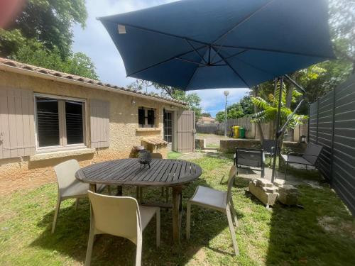 une table en bois avec des chaises et un parapluie bleu dans l'établissement Jolie petite maison Avignon - Montfavet, à Montfavet