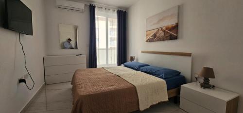 a bedroom with a bed and a tv and a window at Central Apartment Sliema John in Sliema