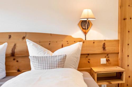 a bedroom with a bed with a wooden headboard and a lamp at Ferienwohnung Alpin - Reit im Winkl in Reit im Winkl