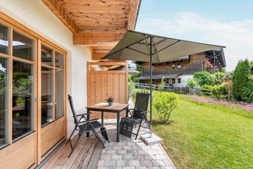 a patio with a table and chairs and an umbrella at Ferienwohnung Alpin - Reit im Winkl in Reit im Winkl