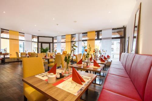 a restaurant with wooden tables and yellow chairs at Montana Hotel Köln-Bonn Airport in Troisdorf