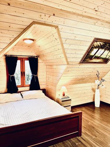 a bedroom with a bed in a wooden room at Mazurska Chatka in Srokowo
