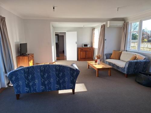 a living room with a blue couch and a table at Oxford Retreat in Martinborough 