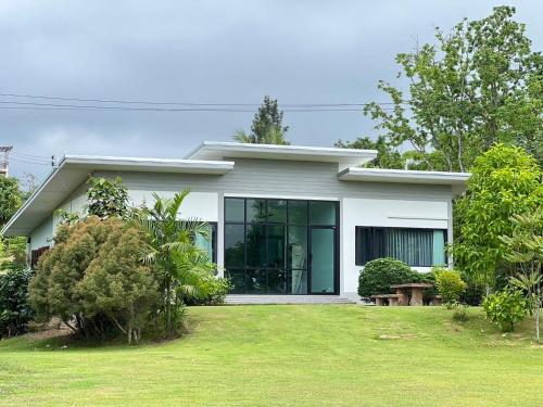 a white house with a lawn in front of it at บ้านสวนจันทร์เจ้า in Wang Nam Khieo