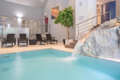a swimming pool with a waterfall in a building at Le Clervaux Boutique Hotel & Spa in Clervaux