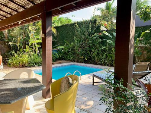 a patio with a table and chairs next to a pool at Pretty house with pool and amazing garden in São Sebastião