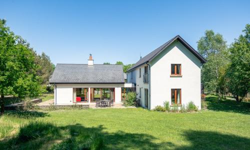 una casa blanca con techo negro y patio en Large Kenmare home sleeping 10. Free use of pool, en Kenmare