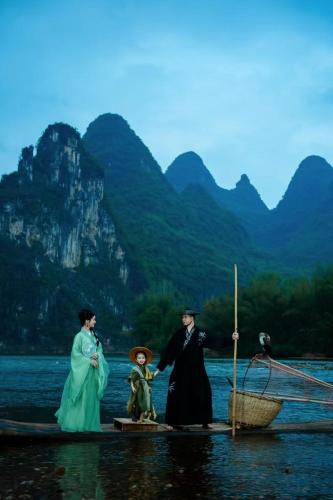 a man and woman standing on a boat in the water at Yangshuo Lisa Boutique Hotel in Yangshuo