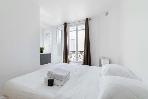 un lit blanc avec deux serviettes dessus dans l'établissement 2 pieces cosy hopital bichat - paris 18 - 2P, à Paris