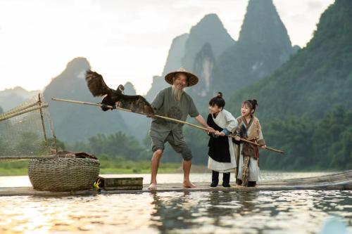 a man and two children are standing in the water at Yangshuo Lisa Boutique Hotel in Yangshuo