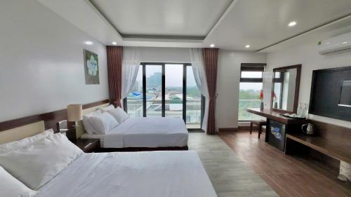 a hotel room with two beds and a flat screen tv at SEN BIỂN HOTEL - FLC Sầm Sơn in Sầm Sơn