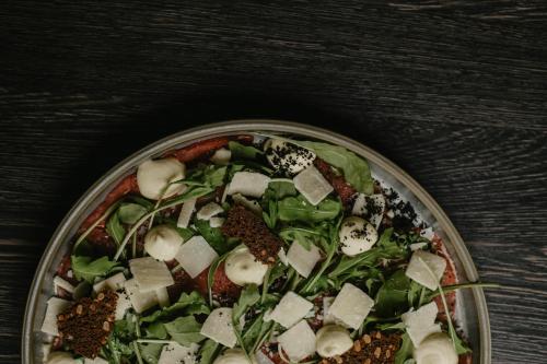a pizza with toppings on a plate on a table at SPA VILNIUS Anykščiai in Anykščiai