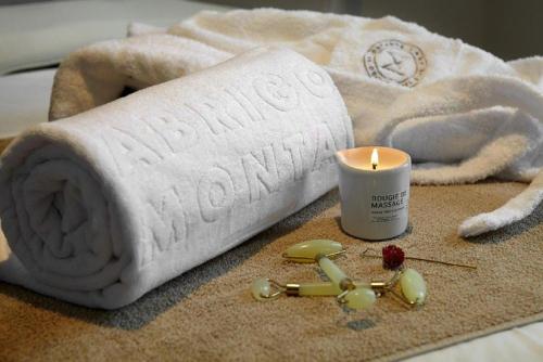 a candle and towels on a bed with a towel at Abrigo da Montanha Hotel Rural in Sabugueiro