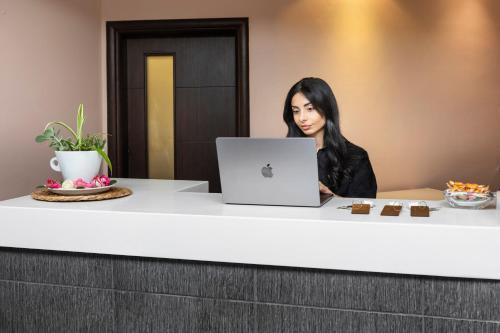 a woman sitting at a desk with a laptop at Ohana Hotel in Kriopigi