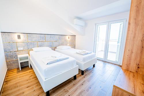 two white beds in a room with a window at Resort Trcol in Novalja
