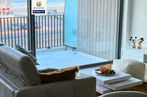 a living room with a couch and a large window at Sea View 1 BR Flat With Pool - Ideal For Couples & Families By SlowayStay Holiday Apartment & Short Term Rental Oostende in Ostend