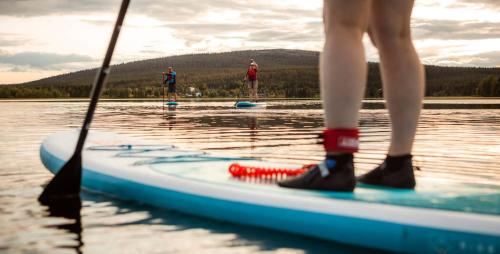 a person standing on a paddle board on the water at Lapland Hotels Kilpis in Kilpisjärvi