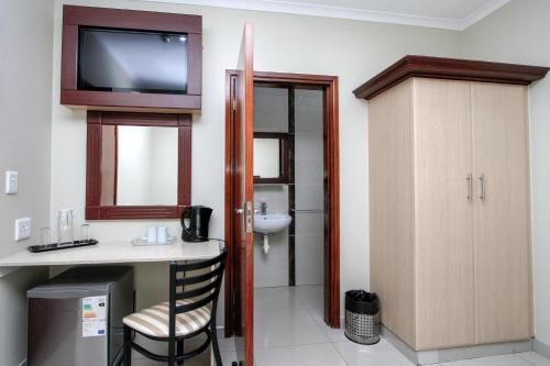 a bathroom with a sink and a television on the wall at PLM Golden Lodge in Durban