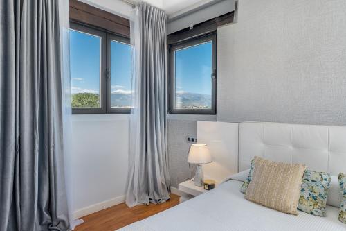 a bedroom with a bed and two windows at Villa Valeria in Las Gabias