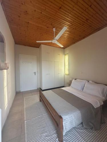 a bedroom with a large bed with a ceiling fan at Les Oliviers Villa with Sea view on Petani Beach in Vovikes