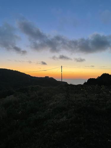 a sunset with a transmission tower in the distance at Les Oliviers Villa with Sea view on Petani Beach in Vovikes