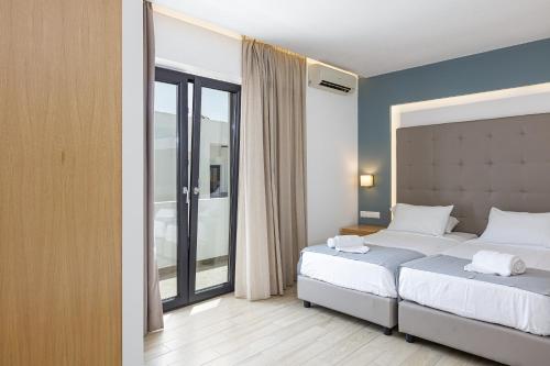 a bedroom with two beds and a large window at Golden Bay Boutique Hotel & Bungalows in Kokkíni Khánion