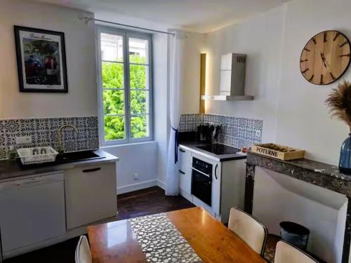 a kitchen with a table and a clock on the wall at Poterne- Logement raffiné avec jardin in Aubeterre-sur-Dronne