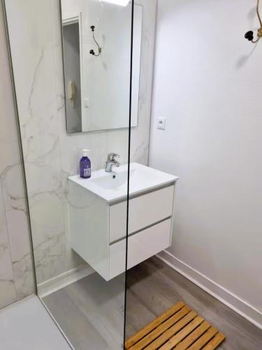 a white bathroom with a sink and a shower at Poterne- Logement raffiné avec jardin in Aubeterre-sur-Dronne