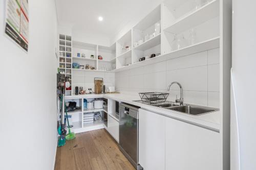 a white kitchen with white cabinets and a sink at ALMA - sun filled stylish beach house in Torquay