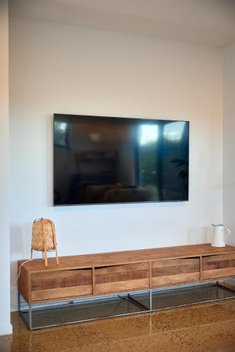 a television on a wall with a chair in front of it at ALMA - sun filled stylish beach house in Torquay