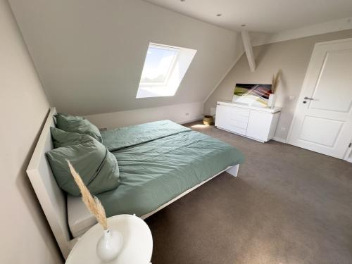 a bedroom with a bed with a green comforter and a window at Stilvolle Dachgeschosswohnung am Teutoburger Wald in Steinhagen