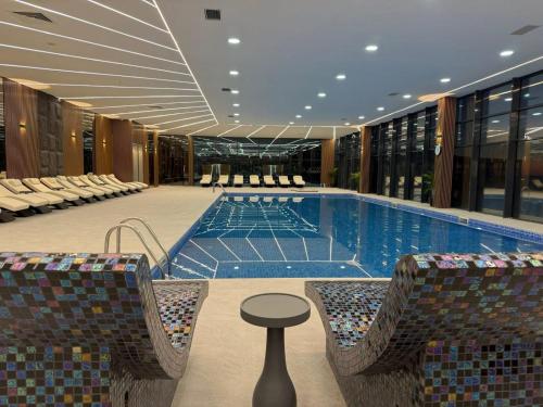 a swimming pool with chairs and a table in a building at Euphoria Batumi Convention & Casino Hotel in Batumi